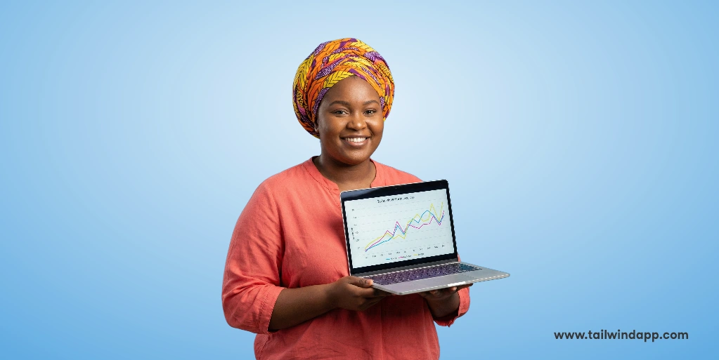 Smiling woman holding a laptop displaying upward-trending graphs, related to Tailwind Turbo Beta results.